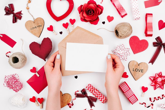 Valentine's Day flat lay with hands holding a card