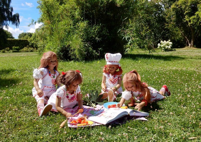 Four dolls having a picnic and reading a book in a park