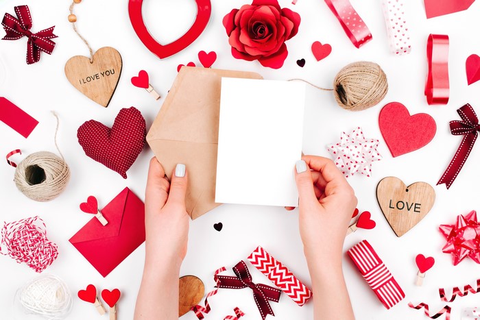 Valentine's Day flat lay with hands holding a card