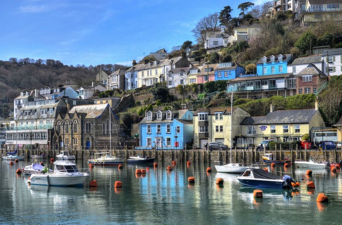 Boats in a harbor with colorful houses on a hill in Looe, Cornwall, England