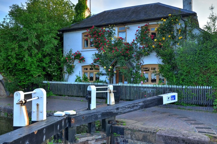 Canal lock house with climbing roses and wooden lock gate