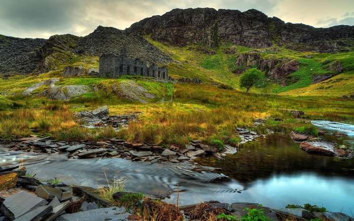 Abandoned stone building in a mountainous landscape with a stream