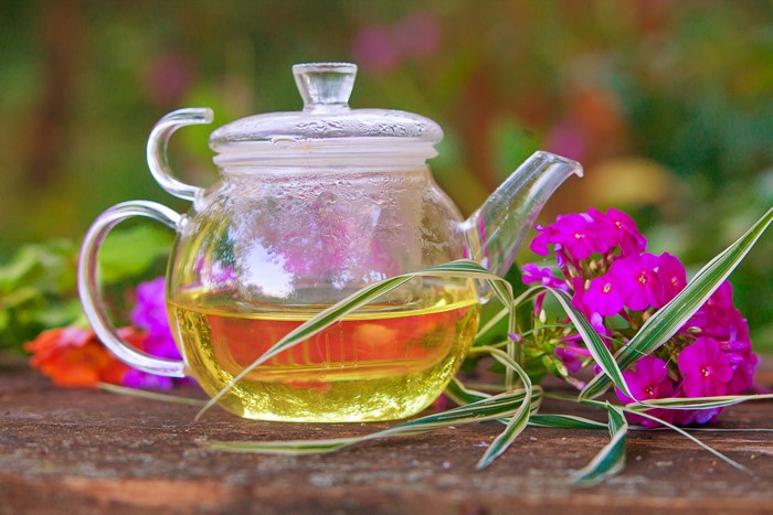 Glass teapot with tea and flowers