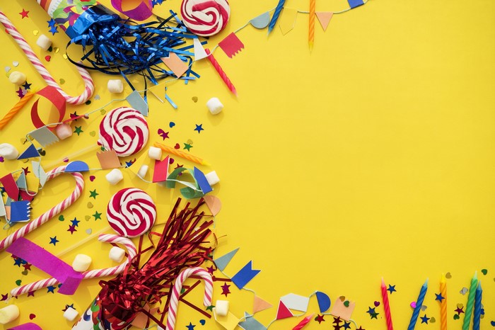 Birthday party decorations and candy on yellow background