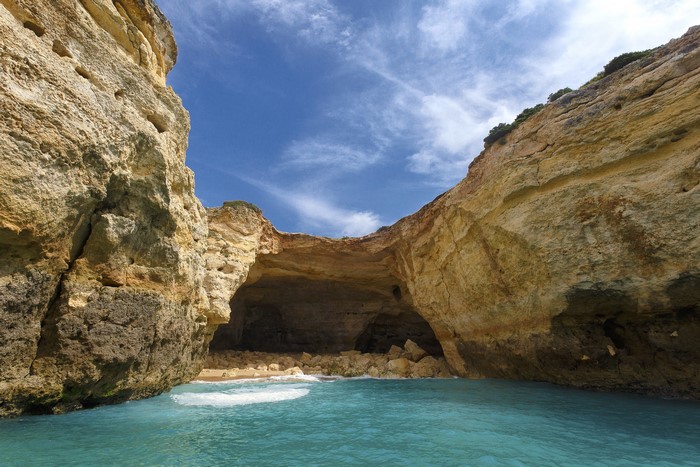 Cave entrance with turquoise water and cliffs in Algarve, Portugal