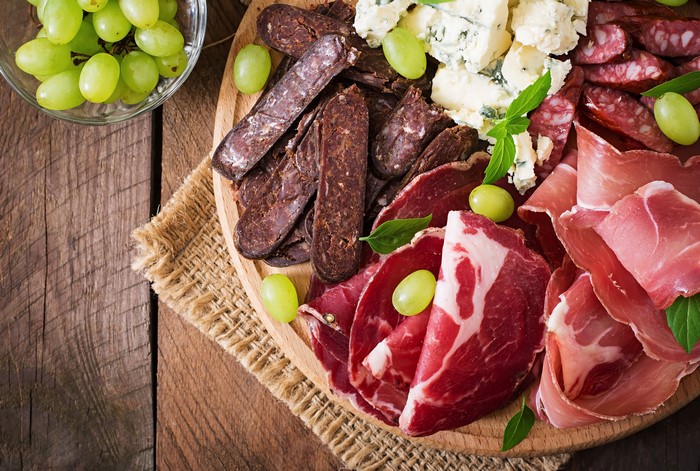 Charcuterie board with ham, sausage, cheese, and grapes