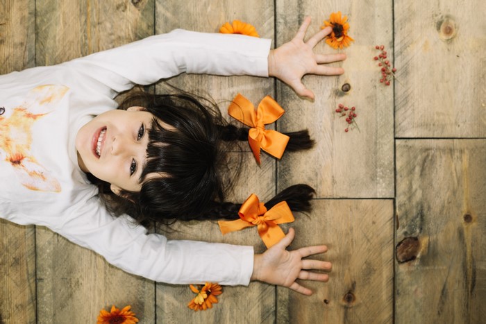 Girl with orange bows on wooden floor