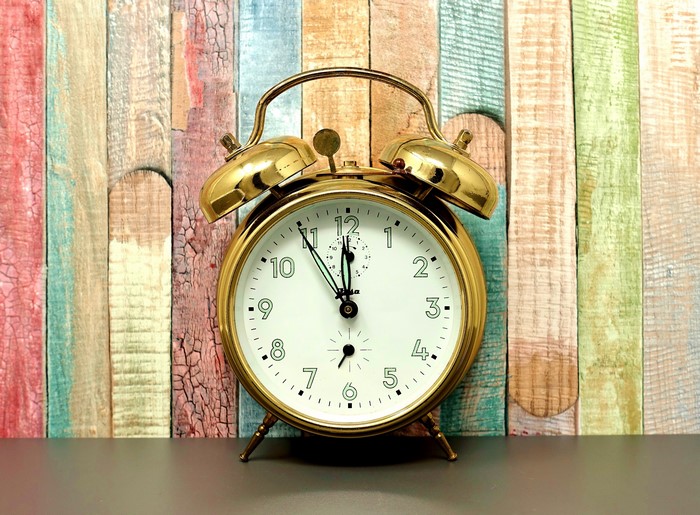 Alarm clock on a colorful wooden background