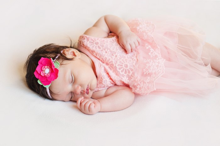 Newborn baby girl sleeping on gray background