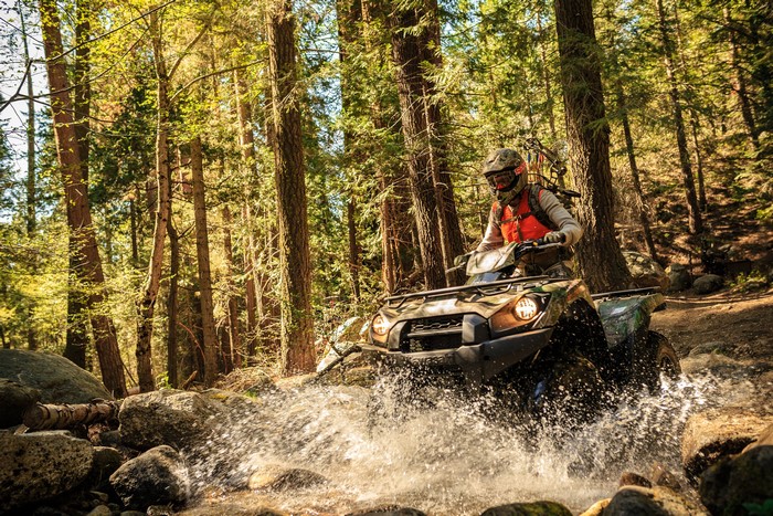 Man riding an ATV through a forest stream