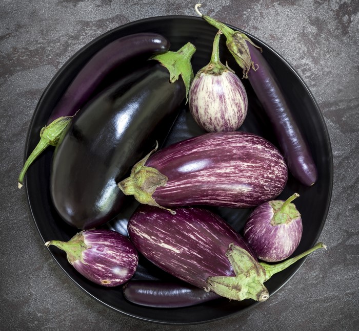 Various eggplants on a black plate