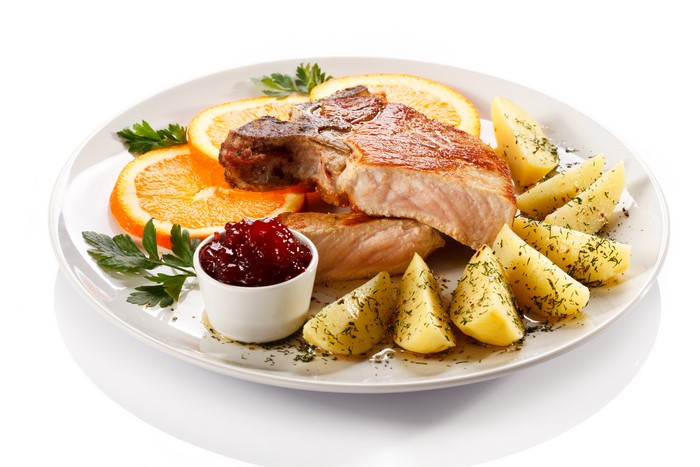 Pork chop with orange slices, potatoes, and cranberry sauce