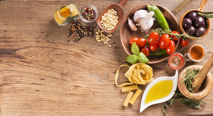 Tomatoes, Garlic, Spices, Pasta, and Olives on a Wooden Table