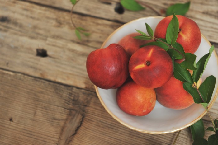 Peaches in a bowl on a wooden table