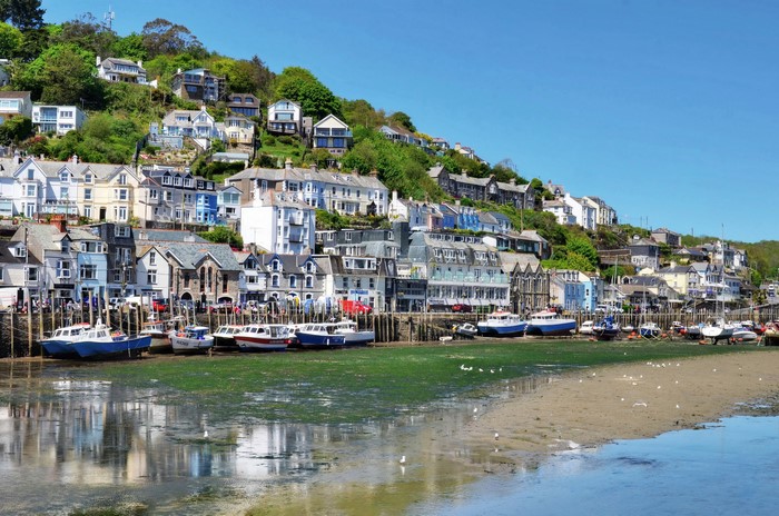 Boats in a harbor with houses on a hill in Looe, Cornwall, England