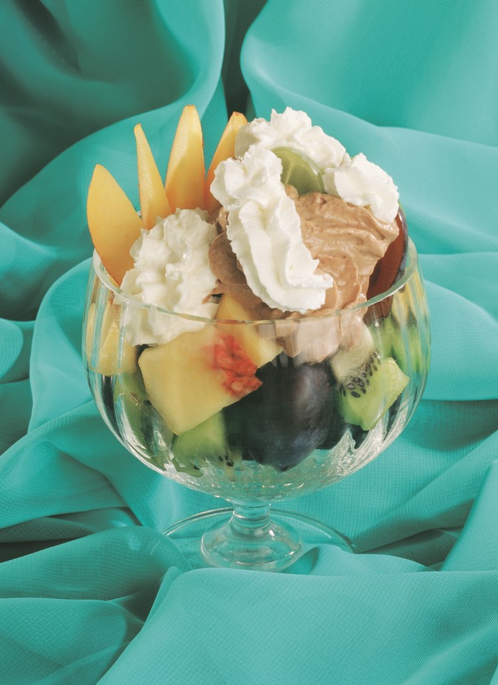 Fruit salad with ice cream and whipped cream in a glass