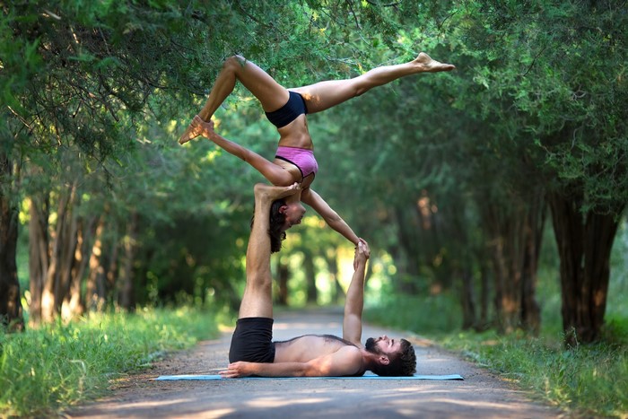 Two people performing acroyoga in a forest path