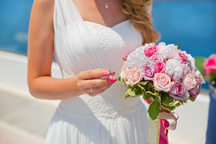 Bride holding wedding rings and bouquet