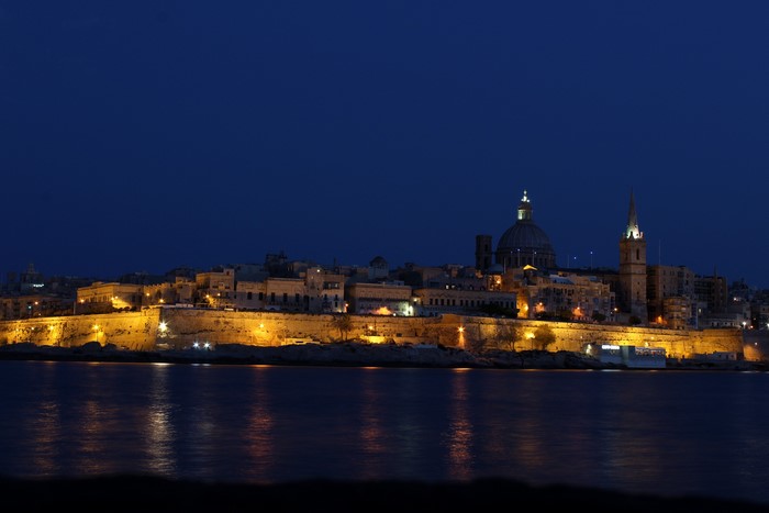 Valletta skyline at night with illuminated fortifications and water