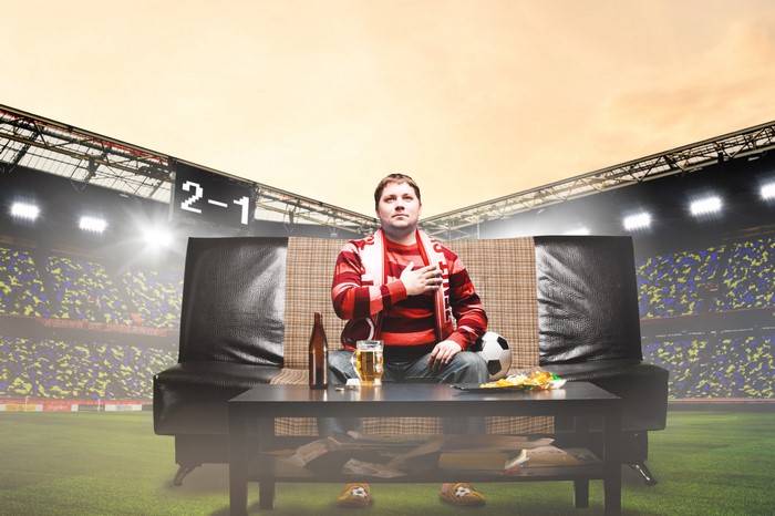 Man watching football game on sofa in stadium