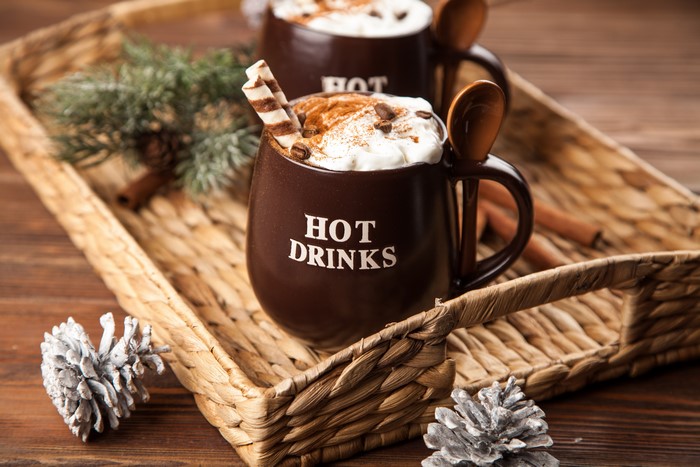 Two mugs of hot drinks with whipped cream and cinnamon