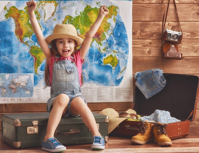 Little girl with suitcase and world map
