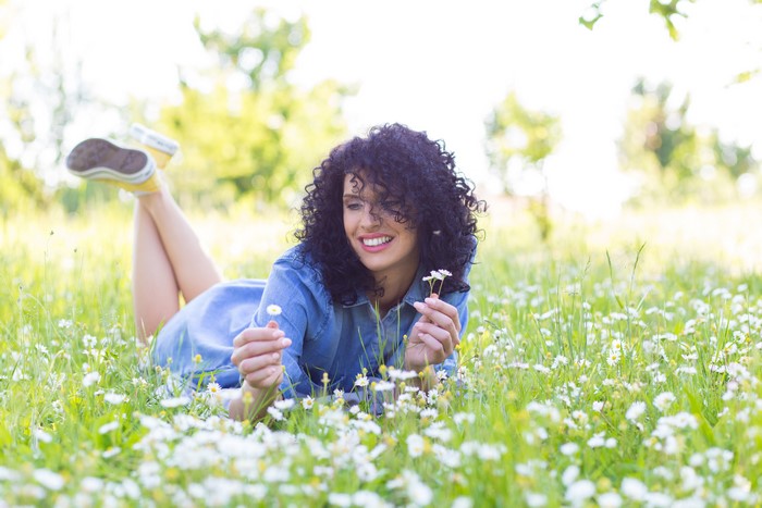 Brunette girl lying in a field of camomiles