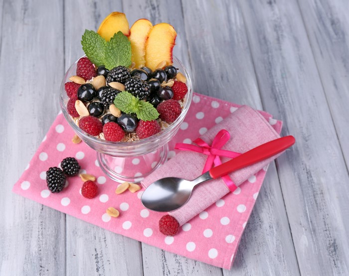 Berry parfait with nuts and mint on wooden table