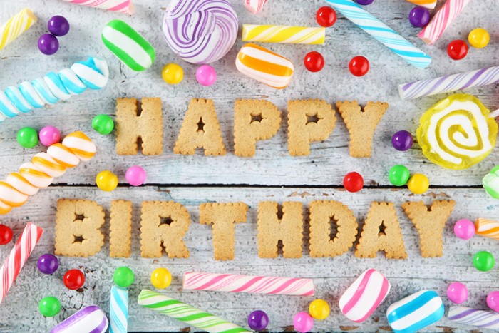 Happy Birthday cookies and candies on wood planks