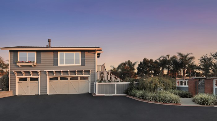 Two-car garage with upstairs windows and flower box at dusk