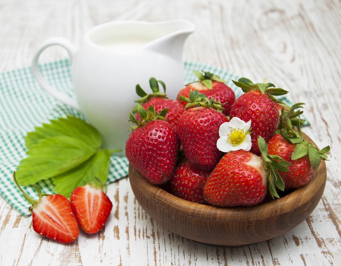 Strawberries in a bowl with a jug of milk