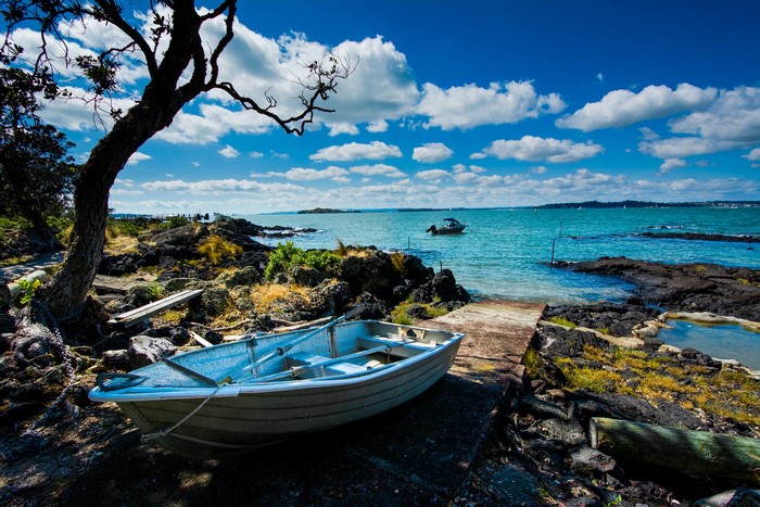 Boat on rocky shore with Rangitoto Island in background