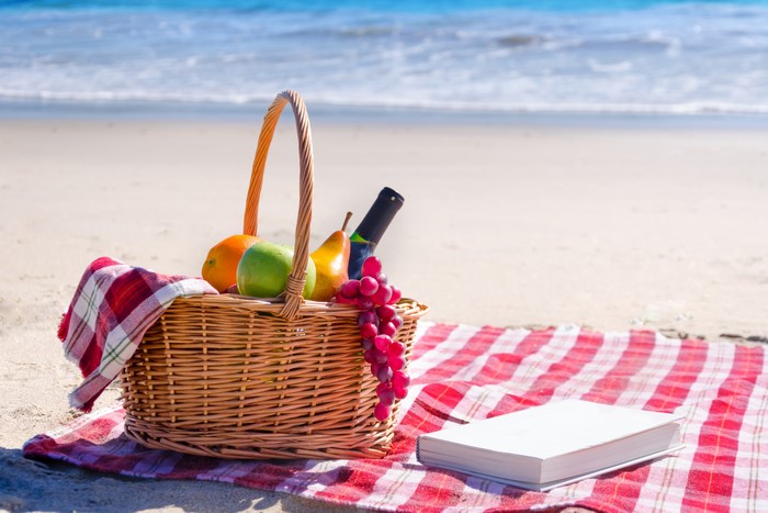 Picnic basket with fruit and wine on a beach blanket