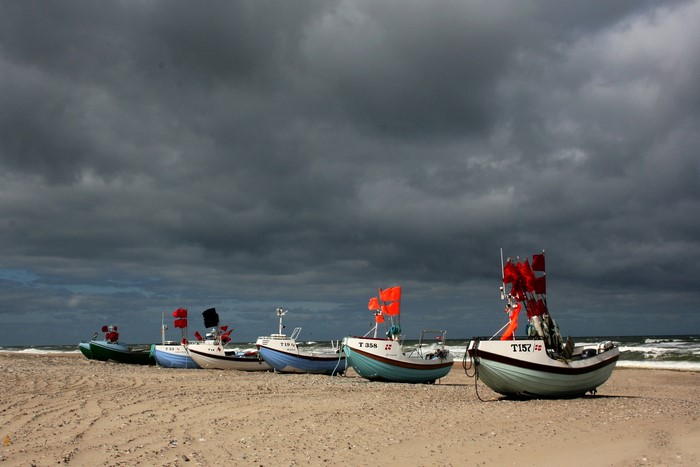 Fishing boats on a sandy beach under a stormy sky