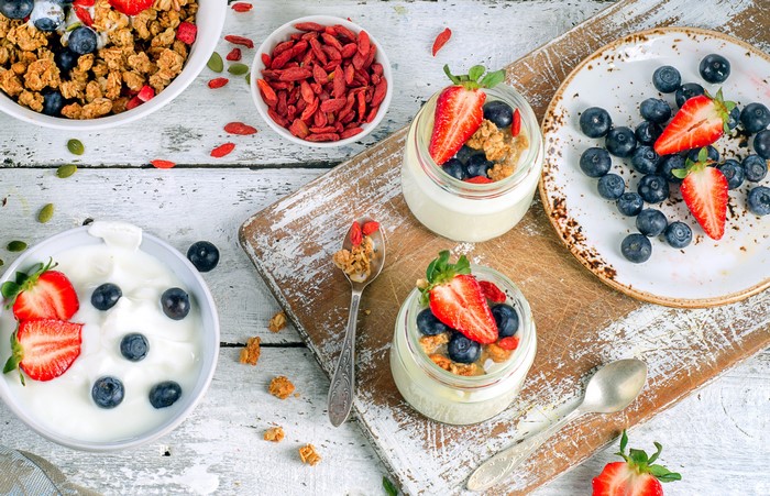 Yogurt parfaits with berries and granola on wooden board