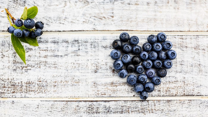 Blueberries arranged in a heart shape on wood planks