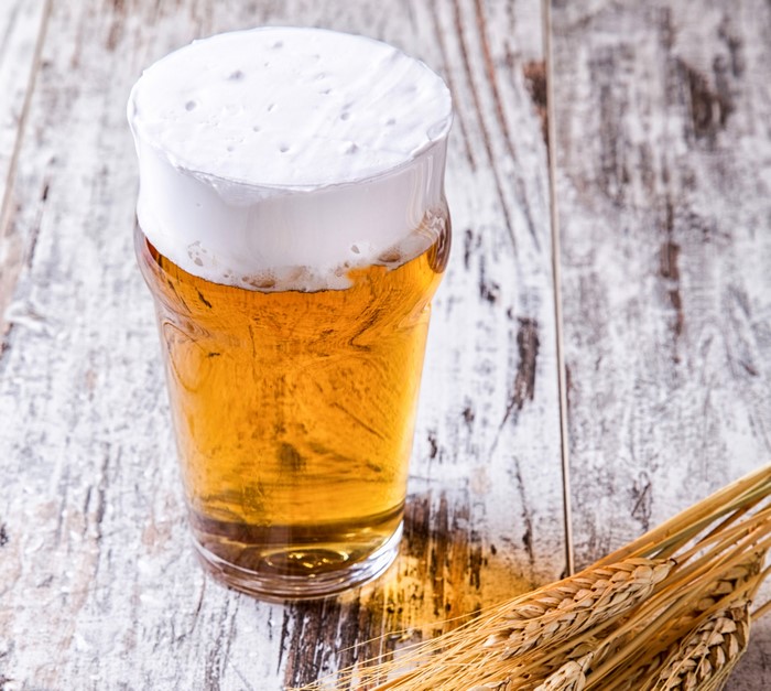 Glass of beer with wheat on wooden table