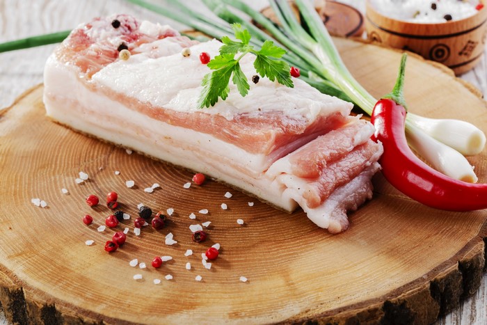 Salo with spices and chili pepper on a wooden board