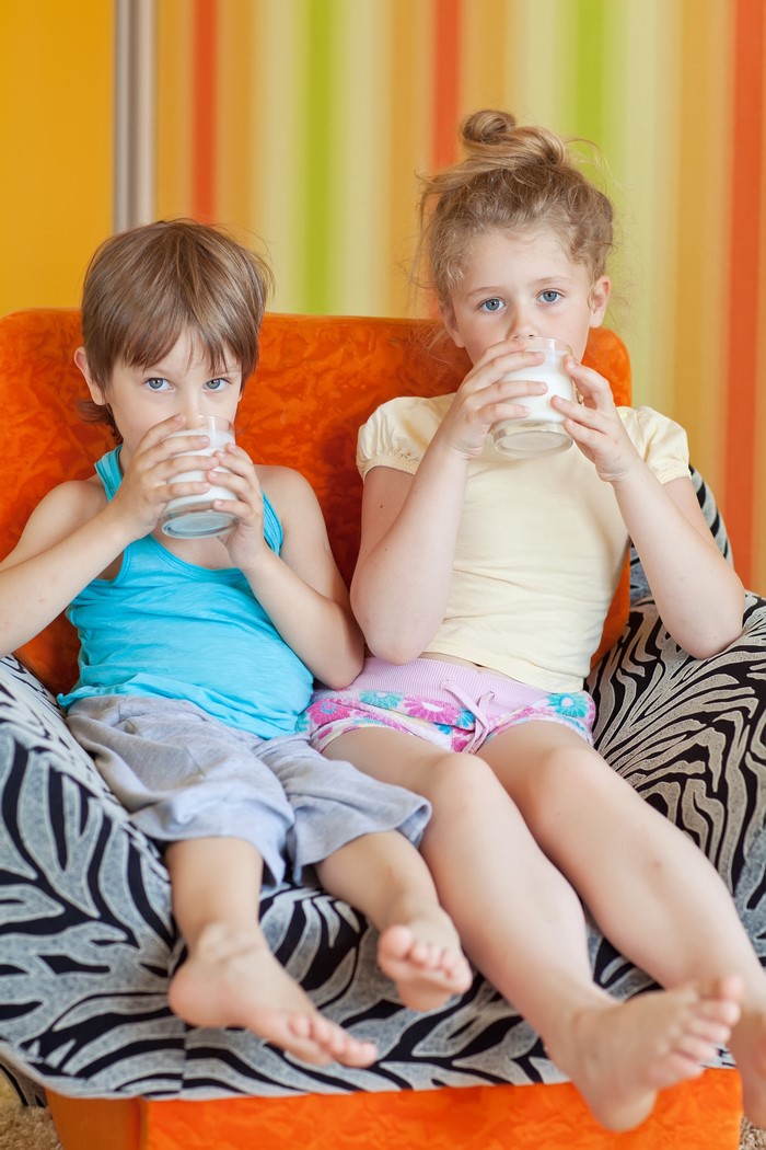 Two children drinking milk from glasses