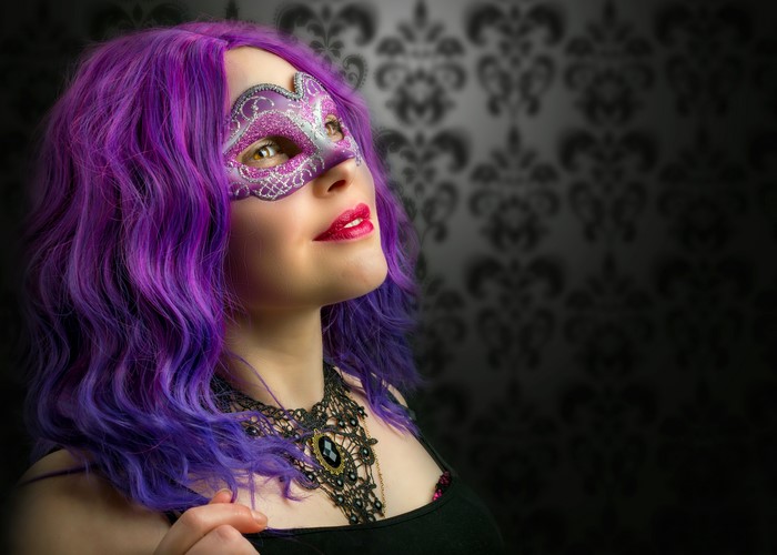 Woman with purple hair wearing a masquerade mask