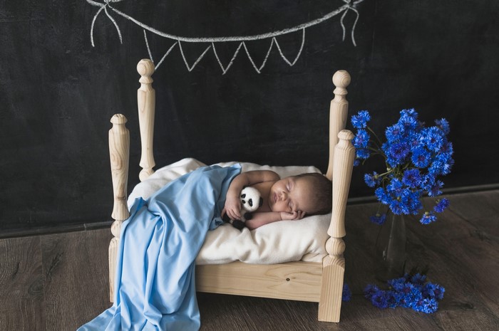 Newborn baby sleeping in a crib with a panda toy