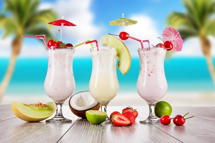 Three tropical cocktails on a beach background