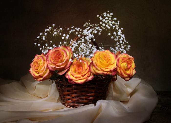 Yellow and red roses in a wicker basket with baby's breath
