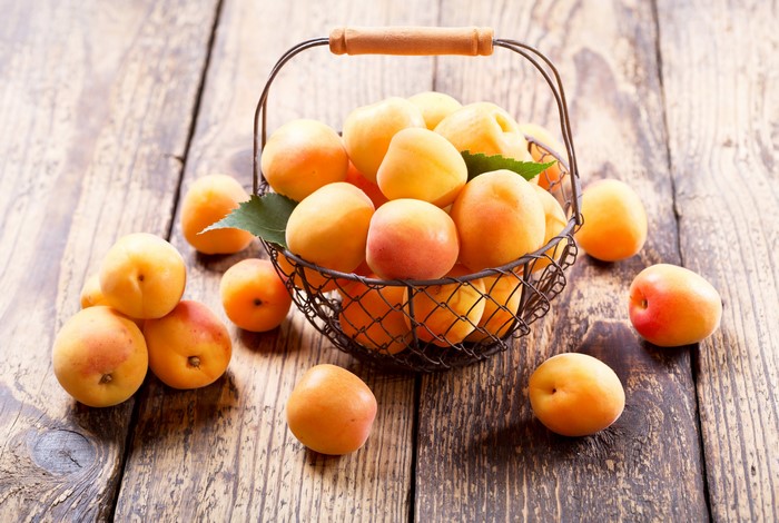 Apricots in a wicker basket on wood planks