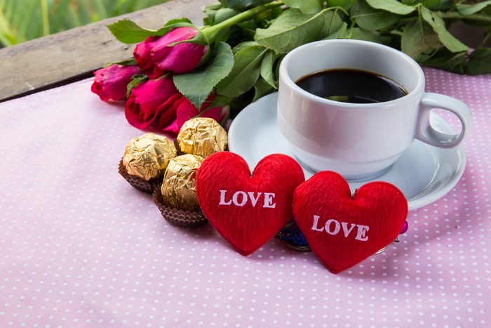 Coffee cup with roses, chocolates, and heart decorations