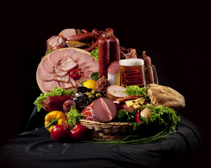 Meat products, sausage, ham, beer, bread, vegetables, tomatoes, wicker basket