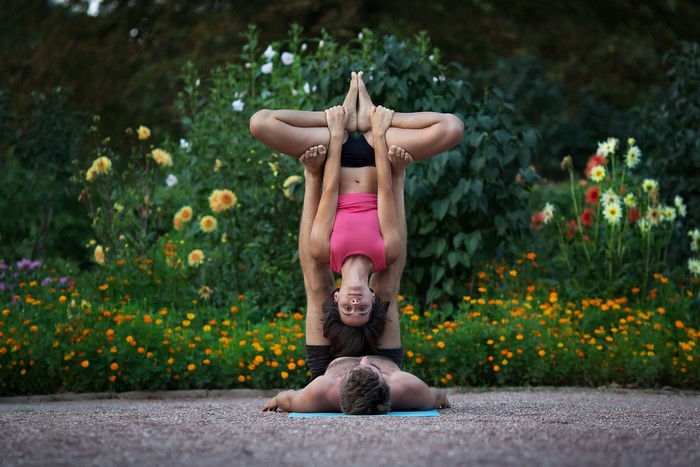 Couple performing acroyoga in a garden