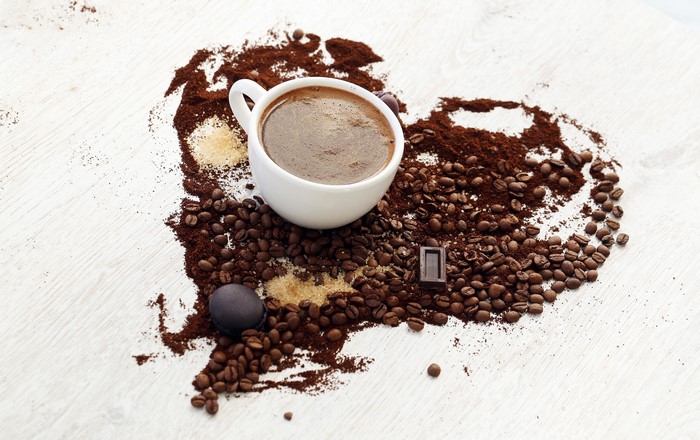 Coffee beans and cup arranged in a heart shape