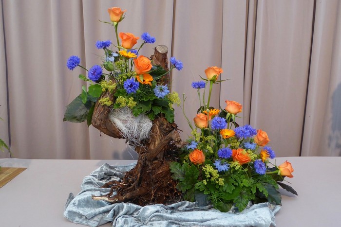 Floral arrangement with roses and cornflowers on driftwood