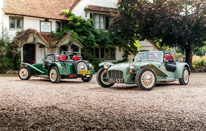Two green Caterham 7 cars parked outside a building